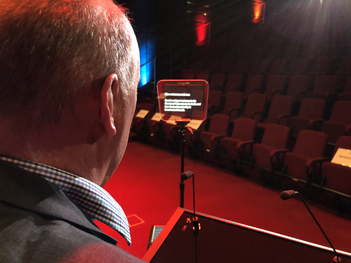 A man is sitting in front of an empty auditorium.