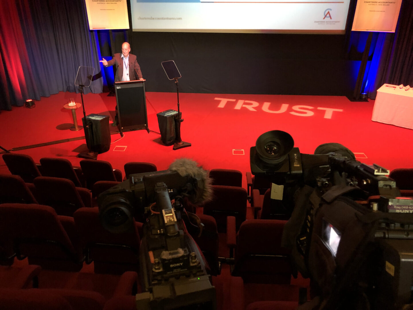 A man standing at the podium in front of a projector.