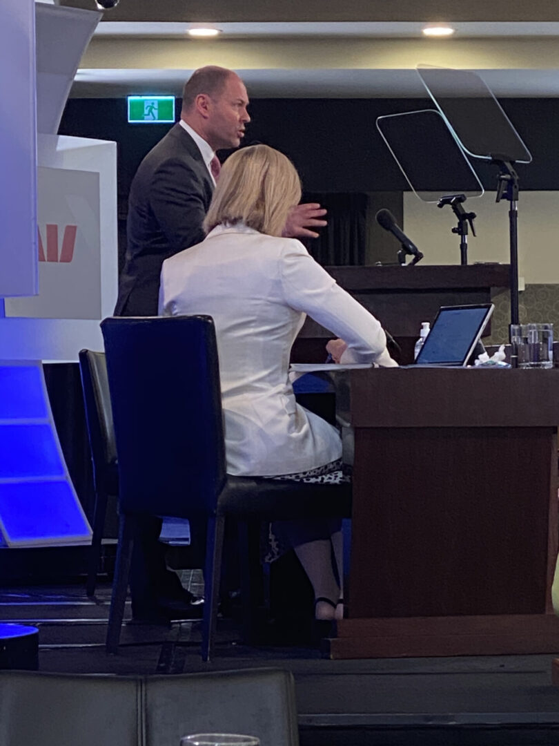 A man and woman sitting at a table with laptops.