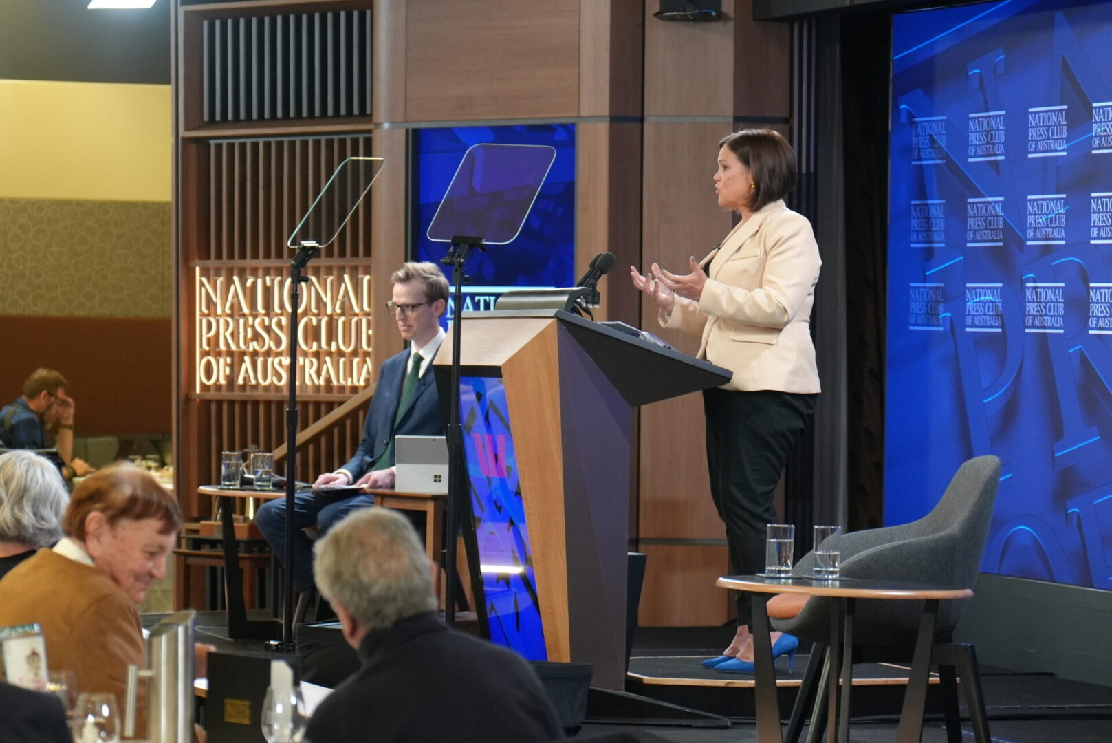 A woman standing at the podium speaking to an audience.