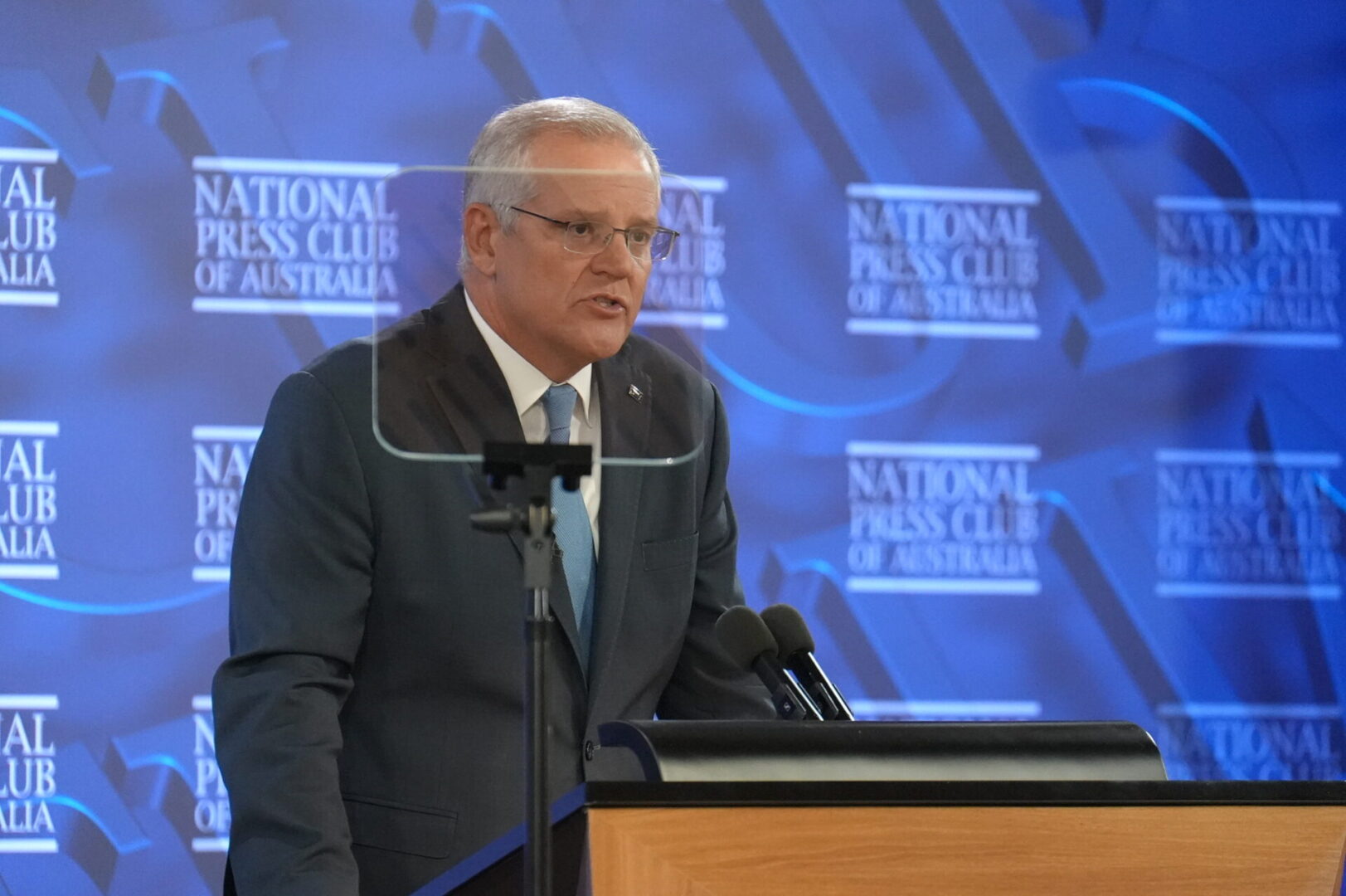 A man in suit and tie standing at a podium.