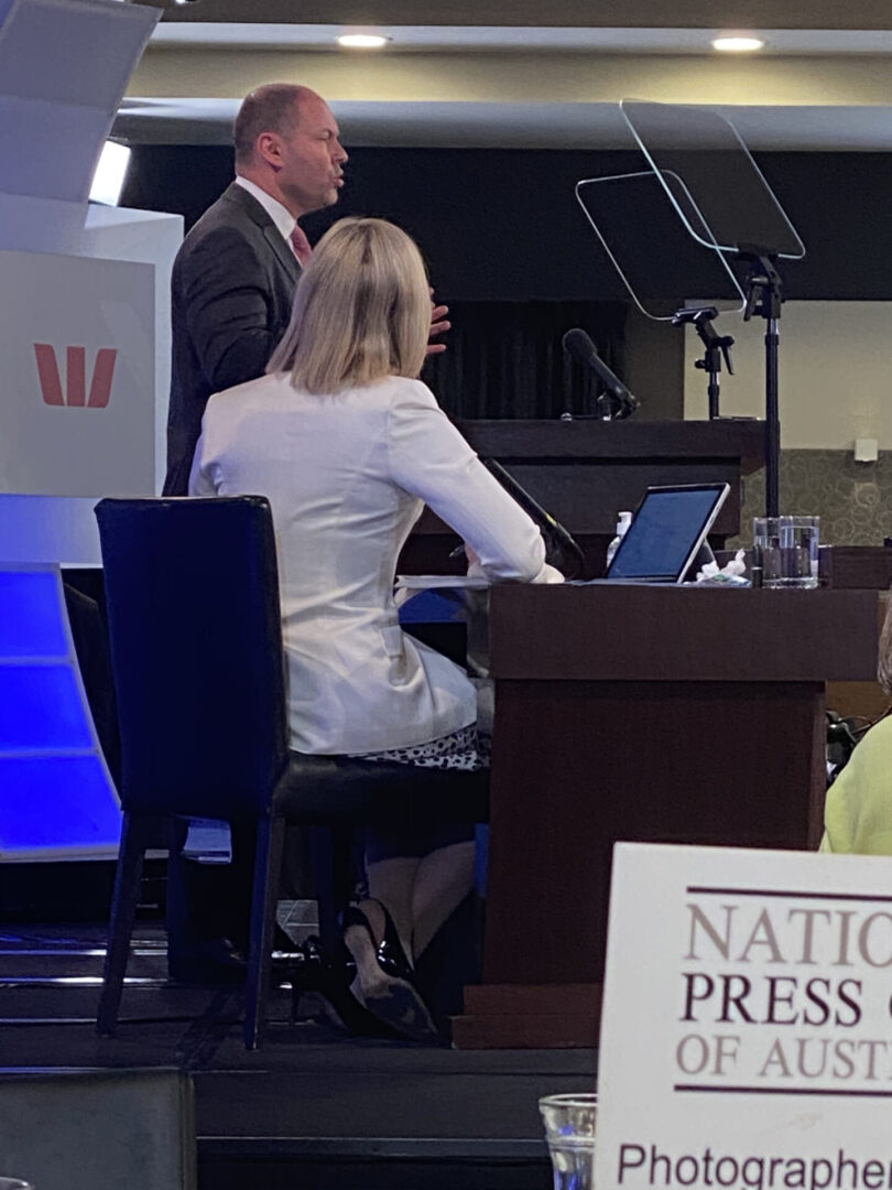A man and woman sitting at a desk with laptops.